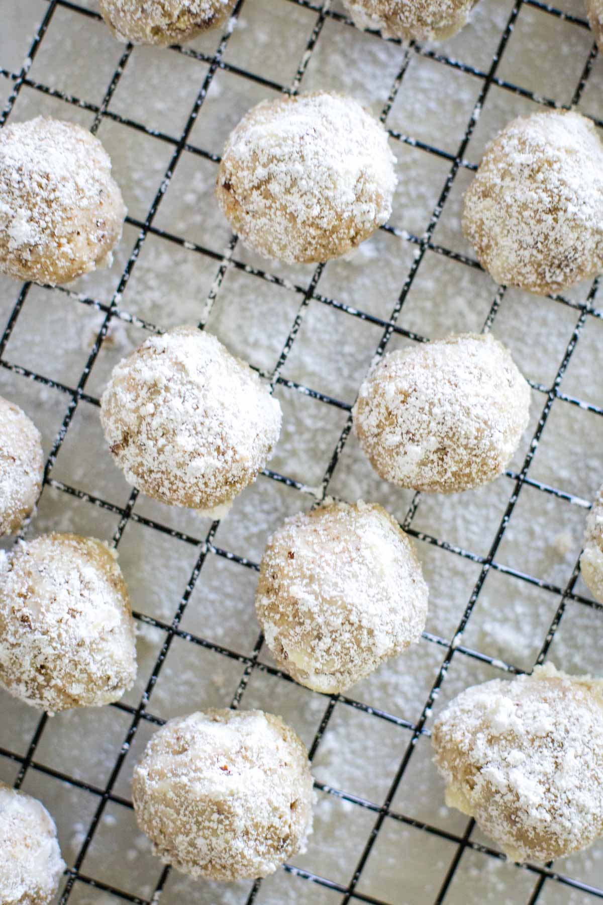 pecan balls on cooling rack in coated in powdered sugar