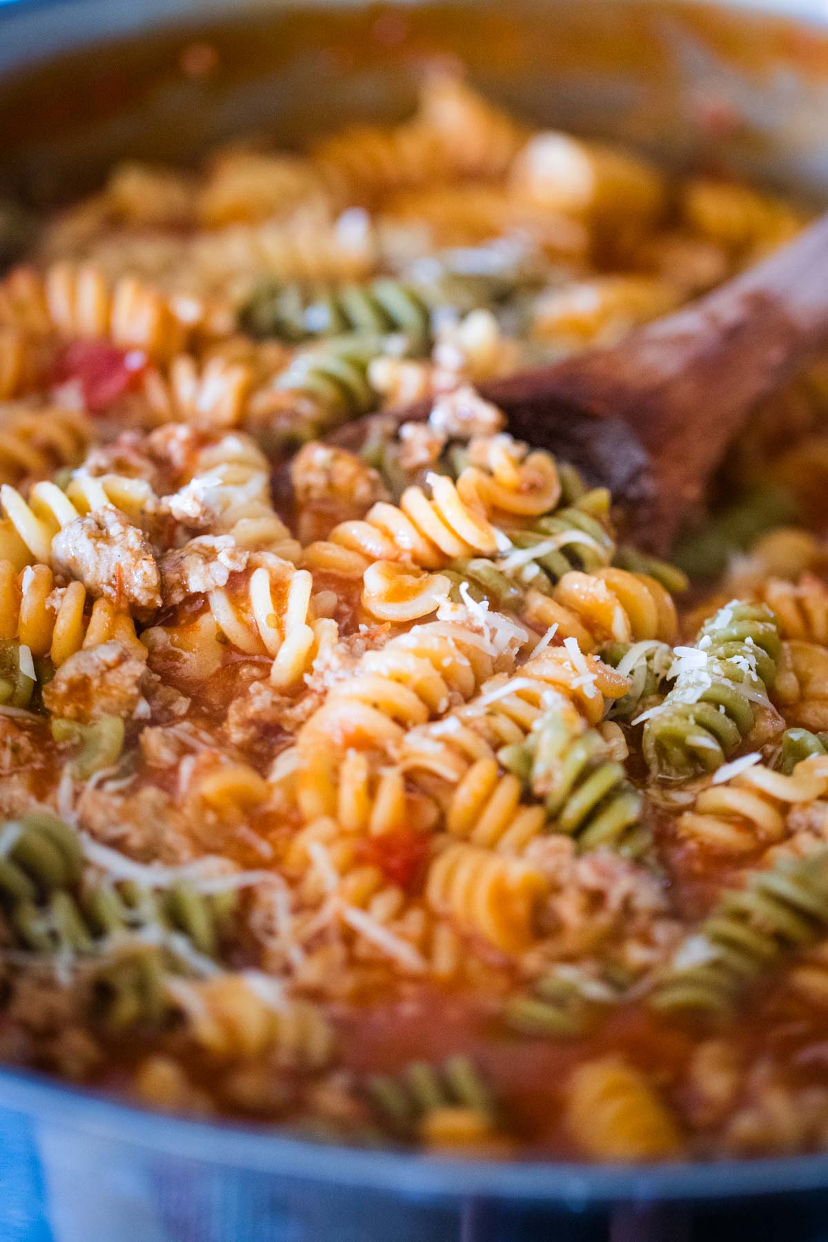 sausage pasta in large pot with wooden spoon