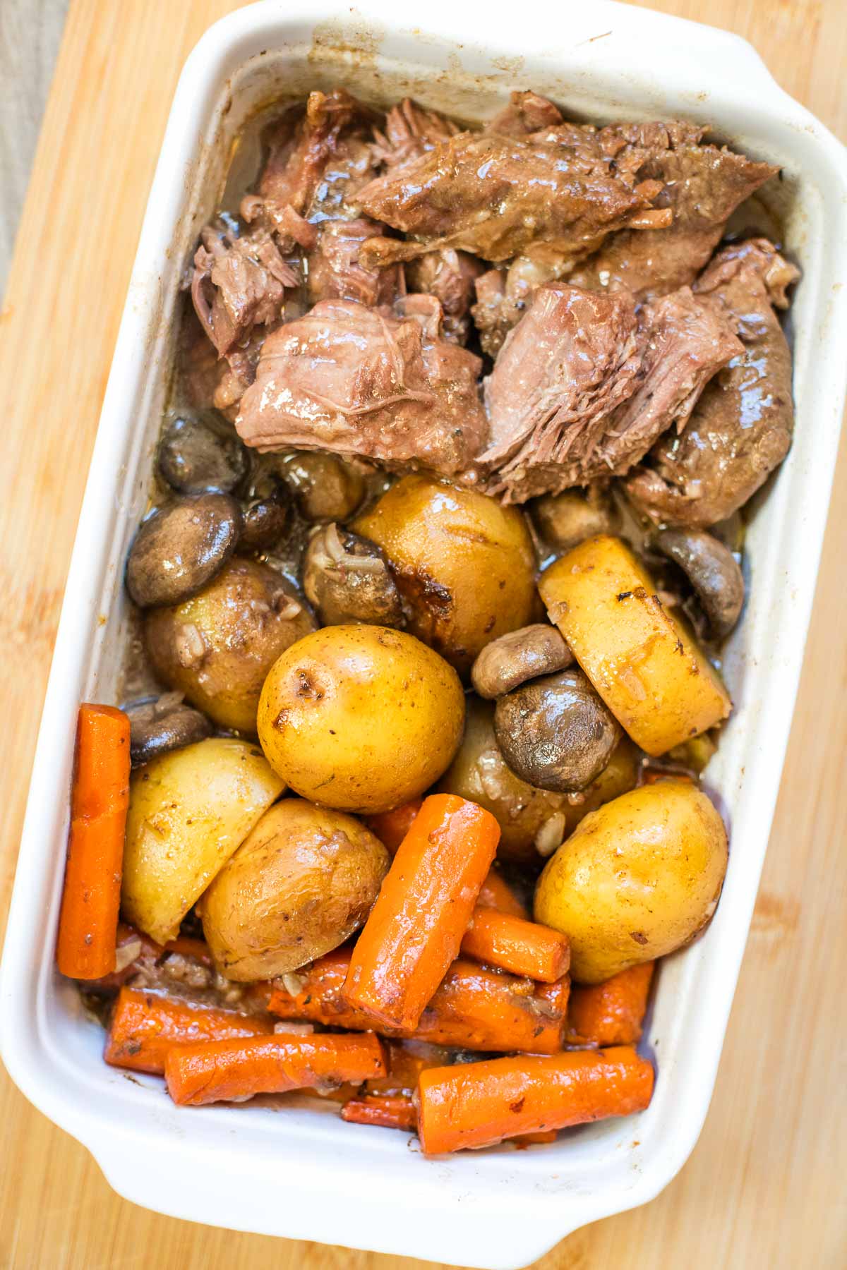 pot roast with carrots, mushrooms and potatoes in large serving dish